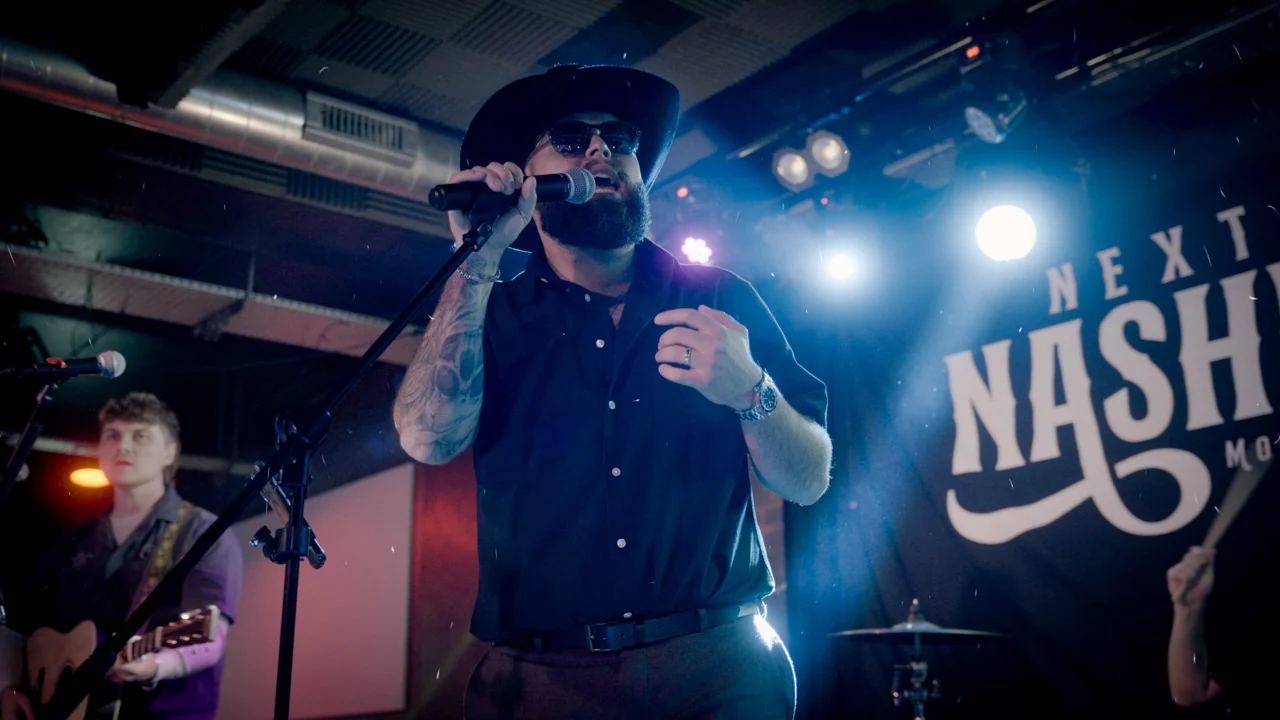 Next Stop Nashville frontman singing under blue stage lights