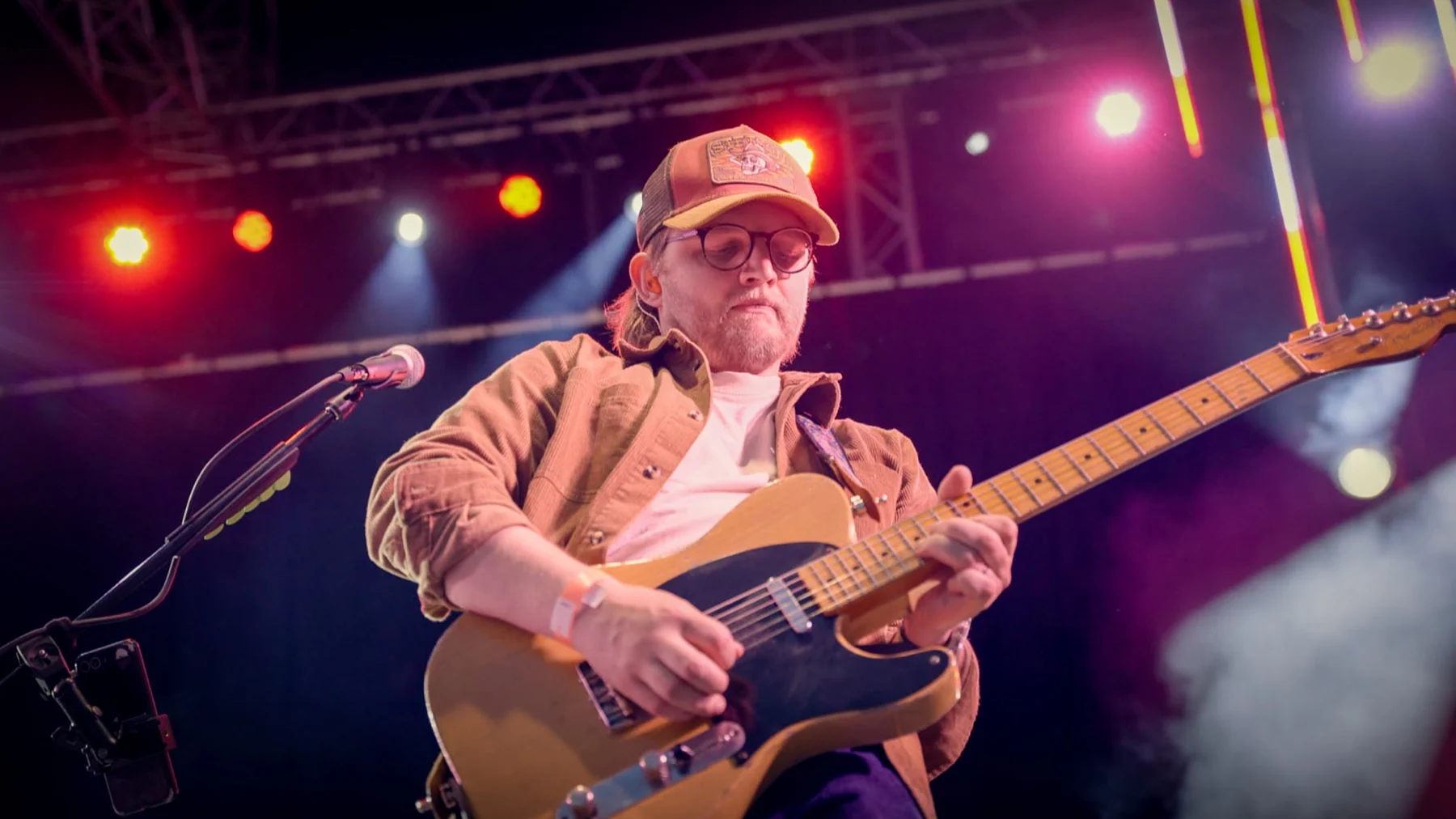 Next Stop Nashville guitarist playing beneath red and purple festival lights